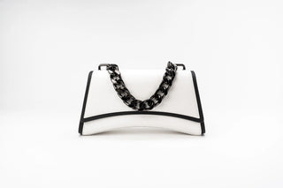 A white leather handbag with black trim and a chunky black chain handle, photographed