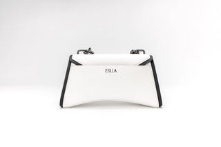 A white structured handbag with black trim and silver-tone hardware, featuring the brand name 'ESLA'
