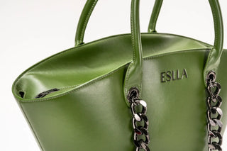 An olive green leather handbag with silver chain handles and the brand name 'ESCLA'.