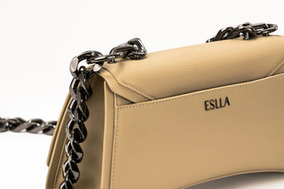 A beige leather handbag with a structured, curved silhouette, featuring a flap top with black hardware