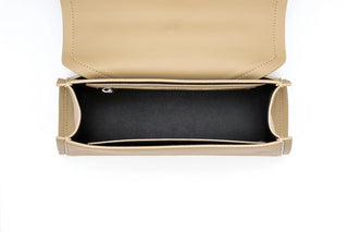 A top-down view of a beige leather clutch bag with its flap open