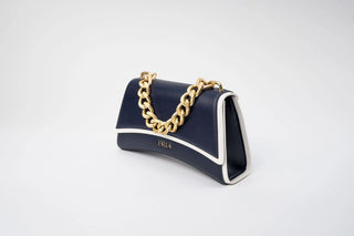 A navy blue leather handbag with a gold chain handle and white piping details
