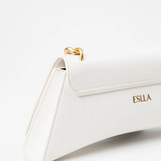 A close-up of a white leather handbag with a gold chain detail and the brand name.