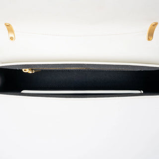Close-up of a white handbag interior showing a black-lined compartment.