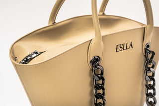 Close-up of a beige leather handbag with black chain handles and the brand